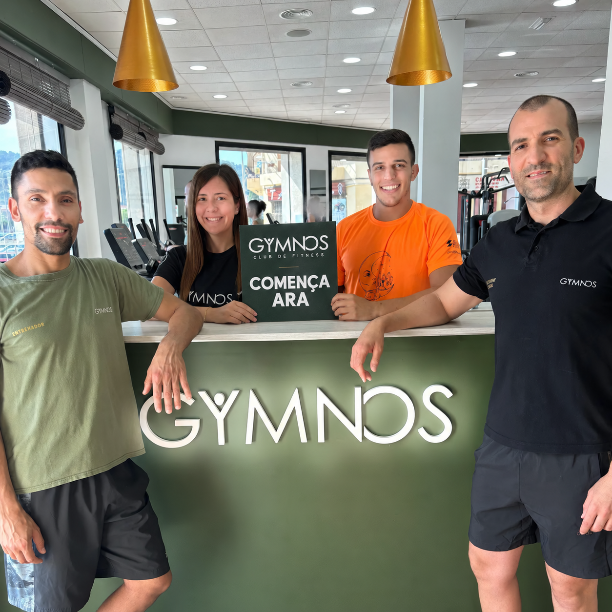 Equip de Gymnos a la recepció amb un cartell conceptual que diu Comença ara
